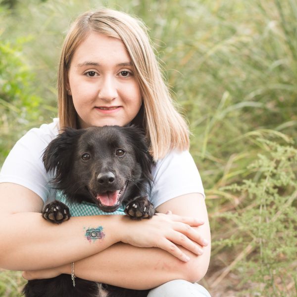 Chica con con su perro negro en la montaña